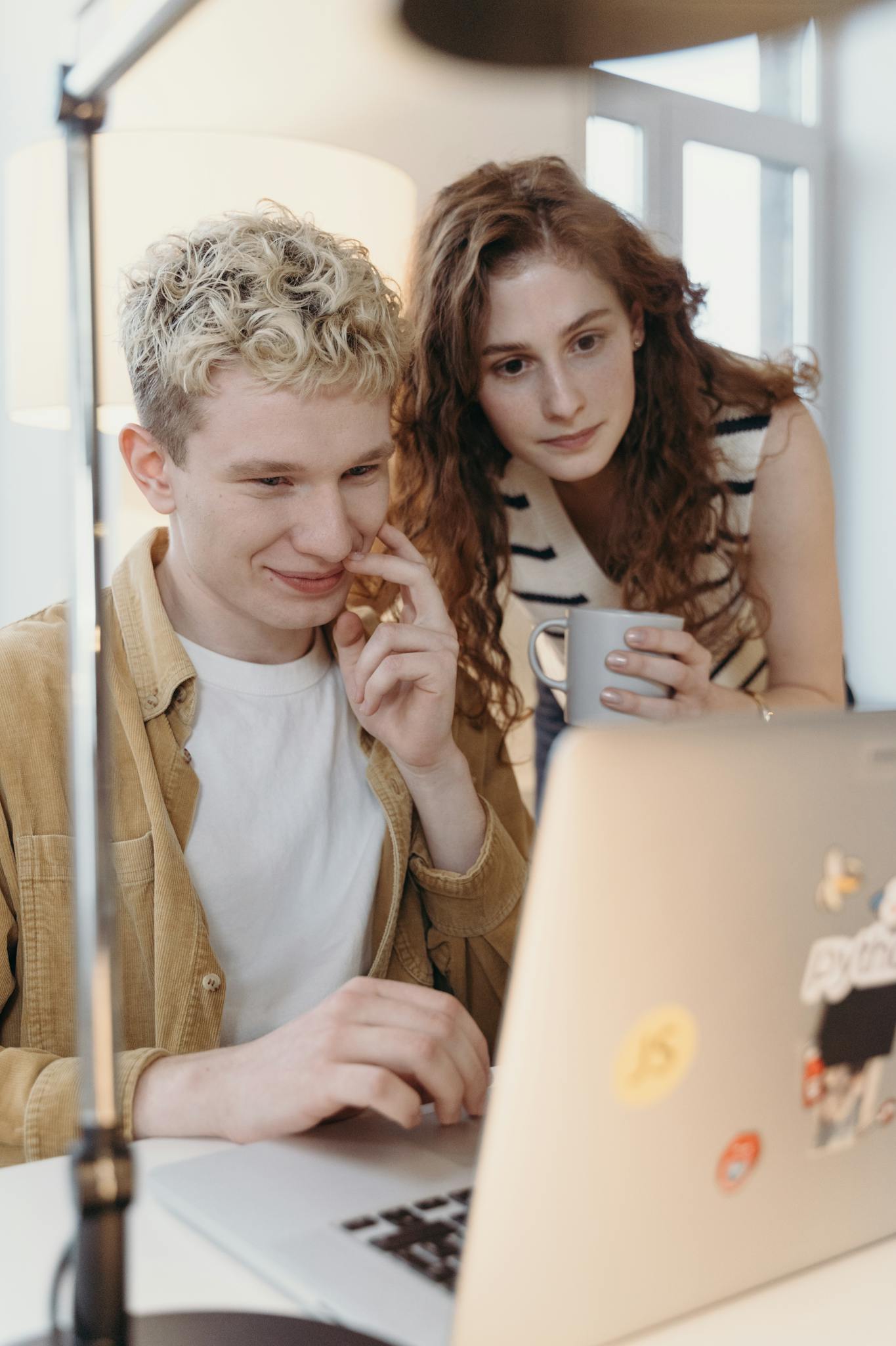 Two young professionals collaborating on a project in a modern office setting.